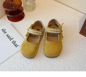 Detalle de merceditas amarillas para niña con tiras de perlas dobles y adorno de lazo