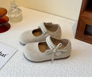Primer plano de zapatos Mary Jane beige para niña con tiras de perlas y lazo