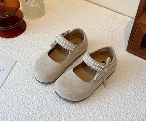 Detalle de zapatos Mary Jane de ante beige para niñas con tiras de perlas y lazo elegante
