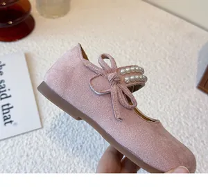 Detalle de cerca de zapatos Mary Jane en gamuza rosa con lazo y perlas para niñas pequeñas.
