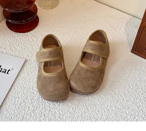 Elegant pair of brown suede girls' Mary Jane shoes displayed on a textured white surface