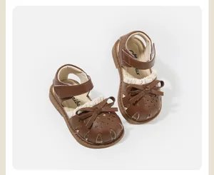 Close-up detail of brown toddler girls' sandals featuring bow and lace ruffle decorations.
