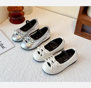 Detailed view of silver and white girls' bow Mary Jane flats on white textured fabric