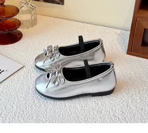 Detail view of silver girl's shoes featuring a cute decorative bow and elastic strap