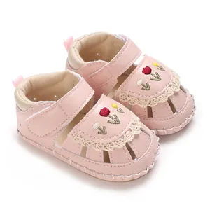 Primo piano di sandali rosa per neonata con ricamo di tulipani e pizzo.