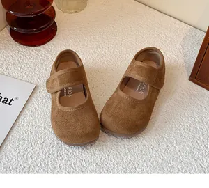 Top-down detail of brown suede Mary Jane shoes for children on textured surface