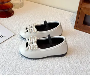 Close-up of white girls' Mary Jane flats with double bow detail and elastic strap.