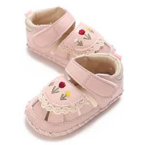 Primo piano di sandali rosa per neonati con ricamo di tulipani e pizzo bianco.