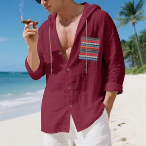 Detail of burgundy linen hooded shirt with bohemian striped pocket on a beach.