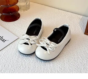 Close-up of white girls' bow leather shoes with soft sole and elastic strap.