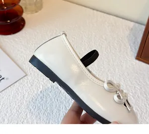 Detailed side view of white children's Mary Jane leather shoe with bow and elastic strap