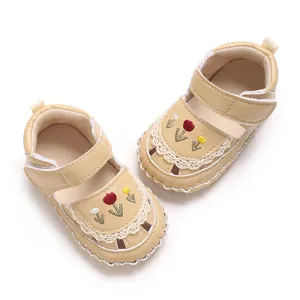 Detail van beige babysandalen met geborduurde bloemen en fijne kanten afwerking