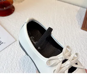 Close-up of white girl's leather shoes featuring a delicate bow and soft elastic strap.