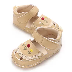 Primo piano dettagliato di sandali beige per neonati con ricami floreali e pizzo