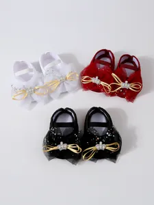 Vue détaillée de chaussures de princesse pour bébé en blanc, rouge et noir avec nœuds