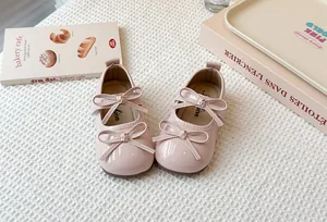 Detailed view of pink girls' Mary Jane shoes with double bows on a textured background.
