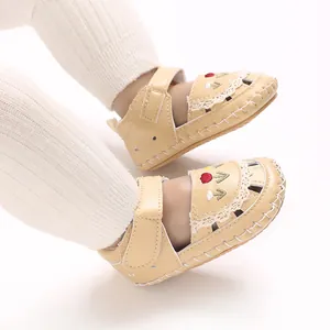 Vista dettagliata di sandali beige per bambini con ricami floreali e pizzo delicato