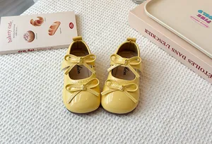 Detail of yellow patent leather Mary Jane shoes for girls featuring double bow accents