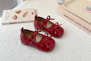 Detail of red patent leather Mary Jane shoes for girls with decorative bows and strap