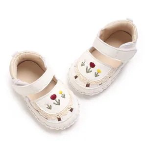 Primo piano di sandali bianchi per neonata con ricami floreali colorati e pizzo