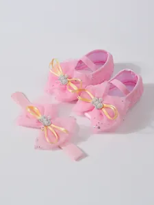 Détail de chaussures de princesse en dentelle rose pour bébé avec nœuds et bandeau