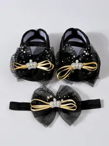 Détail de chaussures de bébé en dentelle noire et ensemble de bandeau assorti.