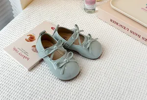 Detailed view of mint green patent leather Mary Jane shoes for girls with bow accents.