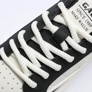 Close-up of white woven rope laces and premium black leather on men's board shoes.