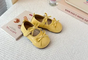 Detailed view of yellow patent leather Mary Jane shoes for girls with double bows