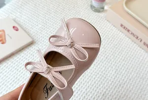 Close-up detail showing the elegant pink patent leather and double bow ties of children's shoes