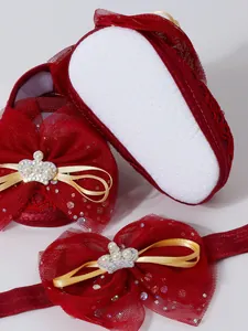 Gros plan de chaussures de princesse pour bébé en dentelle rouge avec nœud couronne