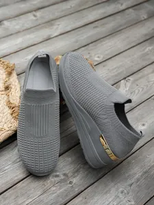 Close-up of grey flyknit wedge sneakers featuring a metallic gold heel accent.