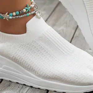 Close-up of white breathable mesh knit platform sneakers for women on wooden floor