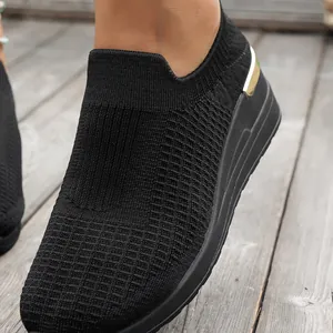 Close-up detail of black breathable fly-knit mesh fabric on women's wedge sneaker