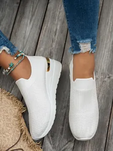 Detailed view of white knit wedge sneakers for women on wooden background