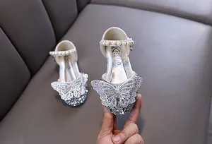 Nahaufnahme von silbernen Prinzessinnenschuhen mit Schmetterlings- und Perlendetails.