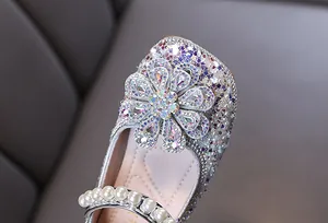 Detailansicht von Mädchen-Prinzessin-Schuhen mit funkelnder Strassblume und Perlenriemen