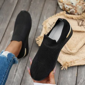 Close-up view of black fly-knit slip-on wedge sneakers with elegant gold heel detail