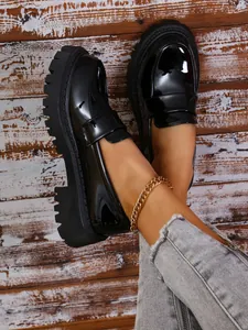 Λεπτομέρεια μαύρα λουστρίνι μοκασίνια πλατφόρμα με χοντρή σόλα και χρυσή αλυσίδα αστραγάλου