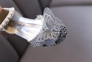 Makroansicht von silbernem Mädchenschuh mit funkelndem Schmetterling aus Strasssteinen