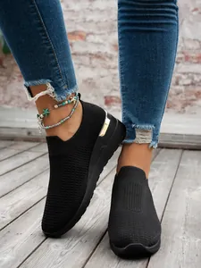 Close-up of stylish black fly-knit wedge sneakers with elegant gold metallic heel accent
