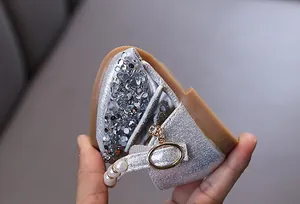 Detailansicht der glitzernden silbernen Prinzessinnenschuhe mit Perlenriemen und Strassschnalle
