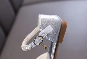 Detailaufnahme von silbernen Glitzerschuhen für Mädchen mit elegantem Perlenband und Anhänger