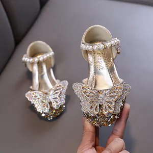 Glänzende goldene Mädchen-Prinzessin-Schuhe mit Strass-Schmetterling und Perlen.