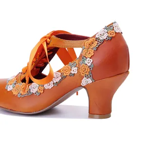 Close-up detail of vintage orange leather Mary Jane heels featuring intricate lace flower embroidery