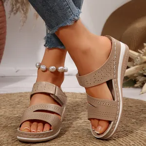 Dettaglio di sandali beige con zeppa con motivi floreali traforati e plateau