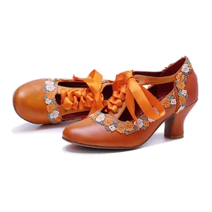 Detailed side view of orange vintage leather Mary Jane heels with lace flowers and ribbons