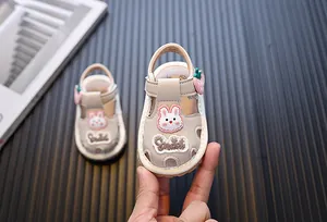 Dettaglio macro di graziosi sandali beige per neonati con motivo coniglio e fragola