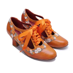 Close-up of orange vintage leather Mary Jane heels with lace floral and satin ribbons.