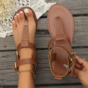 Close-up detail of stylish brown flat Roman thong sandals with double buckle straps